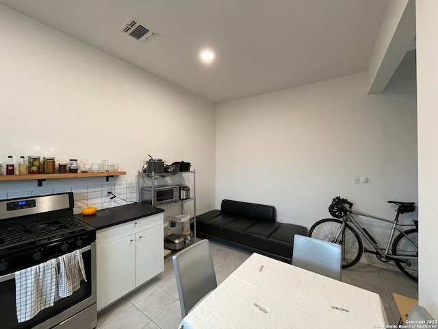 kitchen with light tile patterned floors, stainless steel appliances, dark countertops, visible vents, and white cabinetry