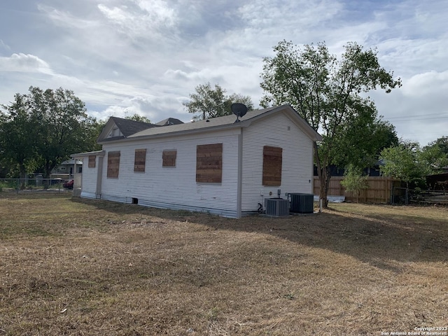 view of property exterior featuring fence, central AC, and a yard