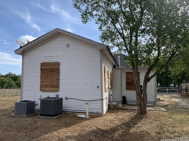 view of side of property with central AC unit and fence