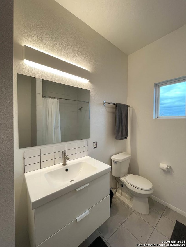 bathroom with decorative backsplash, toilet, curtained shower, tile patterned flooring, and vanity