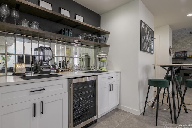 bar with a bar, light tile patterned floors, beverage cooler, and baseboards