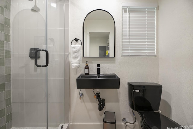 bathroom featuring a textured wall, a stall shower, and a sink