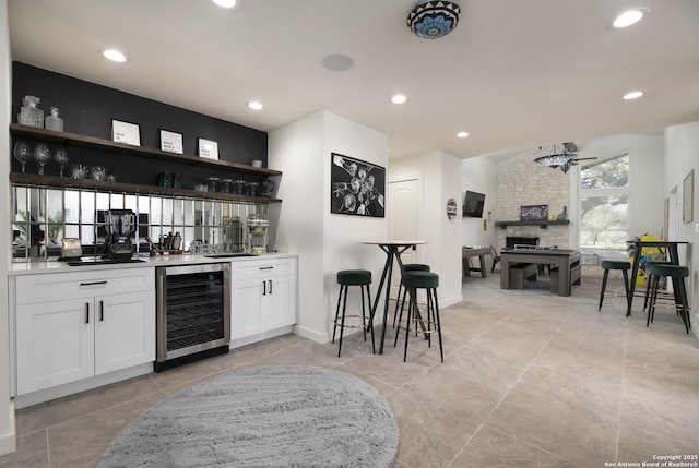 bar featuring recessed lighting, beverage cooler, a fireplace, a ceiling fan, and wet bar