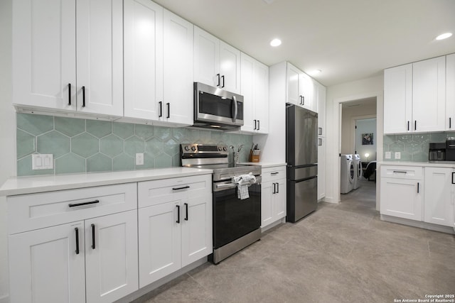 kitchen featuring light countertops, appliances with stainless steel finishes, washing machine and clothes dryer, and white cabinetry