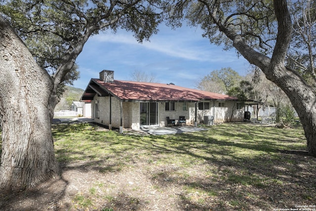 back of house with a chimney, central AC, a lawn, and a patio