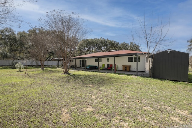 rear view of property with a yard, a storage unit, a patio area, fence, and an outdoor structure