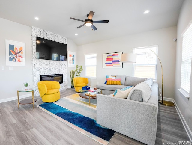 living area with recessed lighting, a large fireplace, baseboards, and wood finished floors