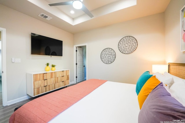 bedroom with recessed lighting, a raised ceiling, visible vents, wood finished floors, and baseboards