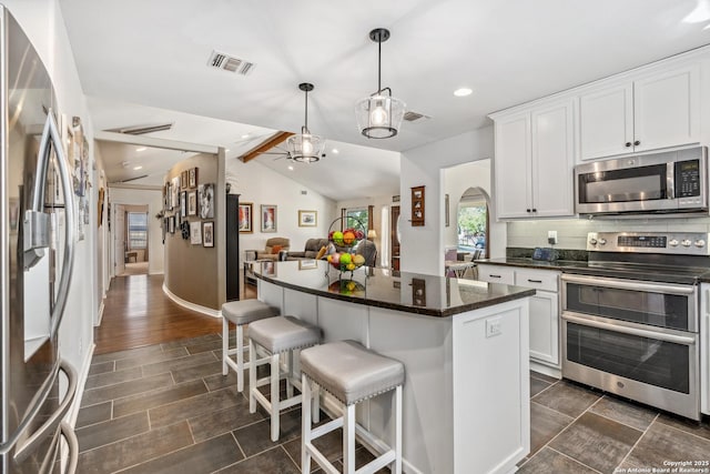 kitchen featuring appliances with stainless steel finishes, arched walkways, visible vents, and tasteful backsplash