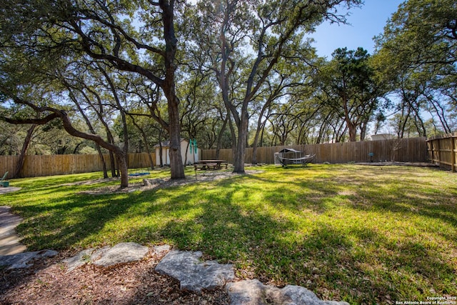 view of yard featuring an outbuilding, a fenced backyard, and a storage unit