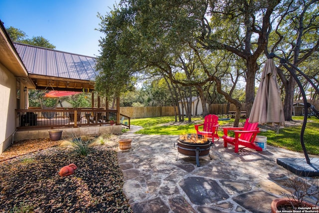 view of patio / terrace featuring a fire pit, an outbuilding, a fenced backyard, and a wooden deck