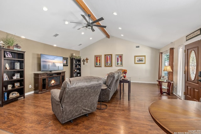 living room featuring dark wood finished floors, vaulted ceiling with beams, a lit fireplace, and baseboards