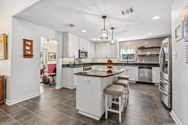 kitchen featuring appliances with stainless steel finishes, dark countertops, visible vents, and decorative backsplash