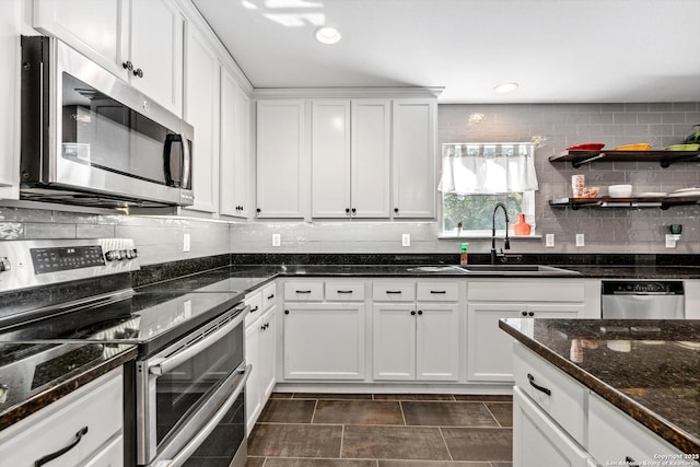 kitchen with stainless steel appliances, a sink, white cabinets, and decorative backsplash