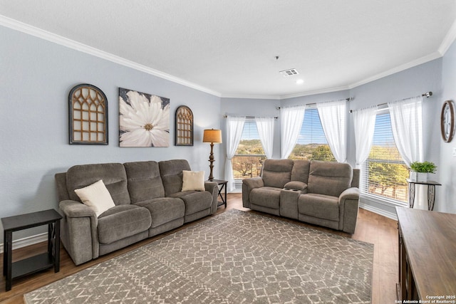 living room featuring baseboards, visible vents, ornamental molding, and wood finished floors