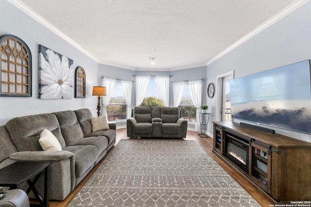 living room with visible vents, a textured ceiling, wood finished floors, and crown molding