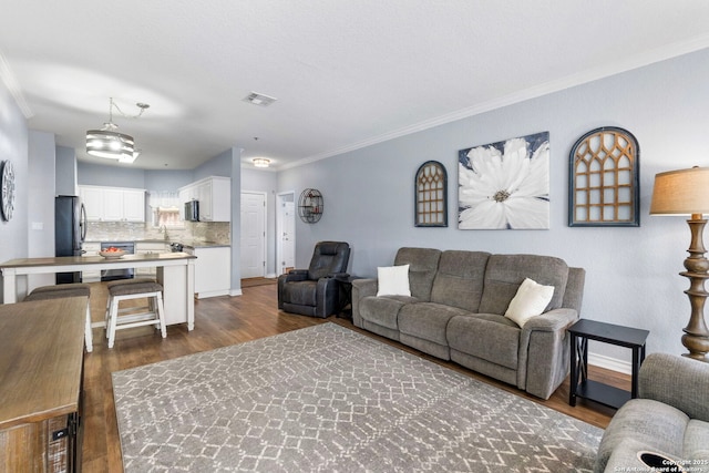 living room featuring baseboards, visible vents, ornamental molding, and dark wood-style flooring