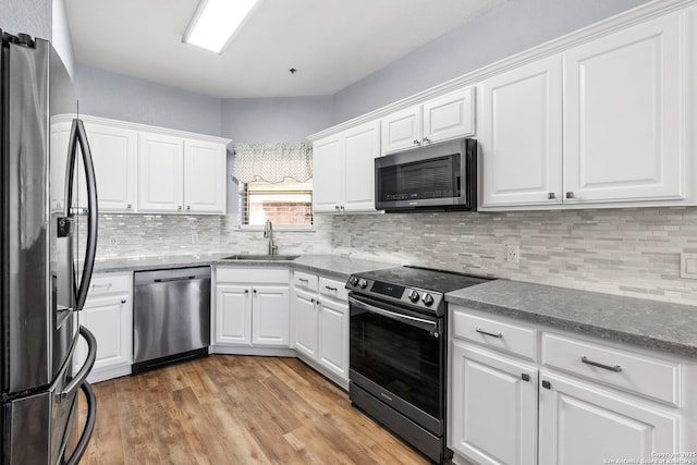 kitchen featuring stainless steel appliances, light wood finished floors, a sink, and white cabinets