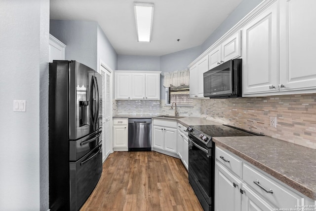 kitchen with stainless steel appliances, wood finished floors, a sink, white cabinets, and tasteful backsplash