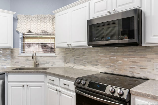 kitchen featuring white cabinets, tasteful backsplash, stainless steel appliances, and a sink