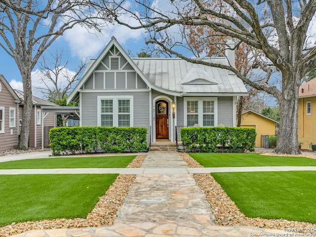 english style home with metal roof, a standing seam roof, and a front lawn