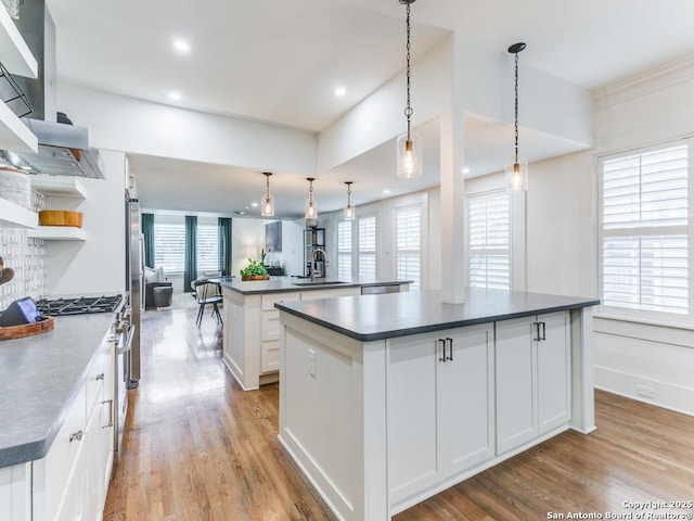 kitchen with a center island, gas range, a healthy amount of sunlight, a sink, and dark countertops