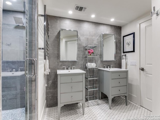 full bath with a stall shower, two vanities, visible vents, and tile walls