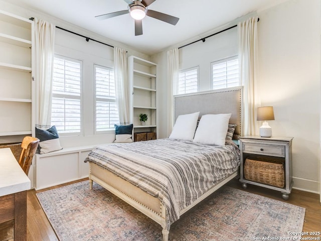 bedroom featuring a ceiling fan, wood finished floors, and multiple windows