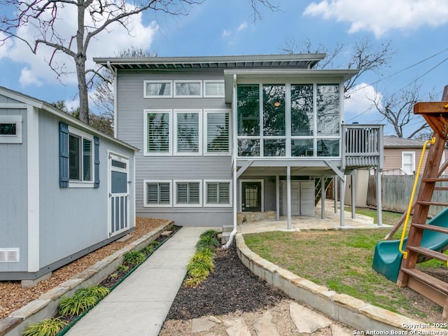 rear view of house with a patio area, fence, and a sunroom