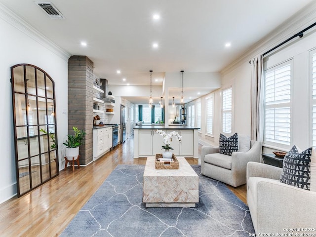 living room featuring recessed lighting, light wood-style flooring, visible vents, and crown molding