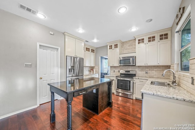 kitchen with dark wood-type flooring, a sink, visible vents, appliances with stainless steel finishes, and light stone countertops