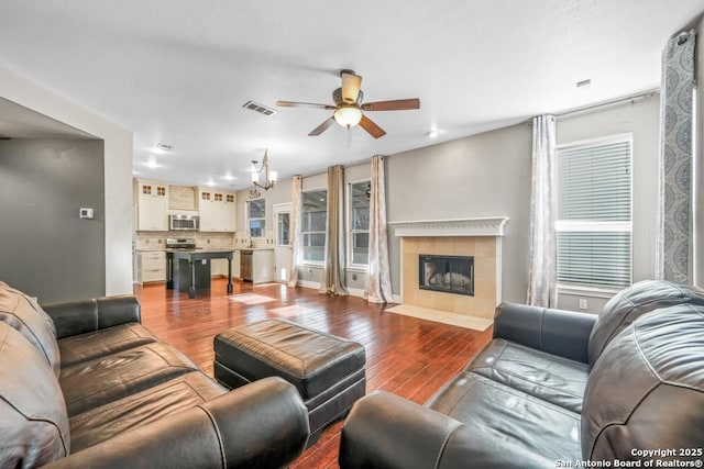 living area featuring visible vents, a fireplace, wood finished floors, and a ceiling fan