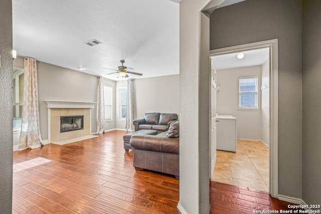 living room featuring visible vents, a fireplace, hardwood / wood-style floors, and ceiling fan