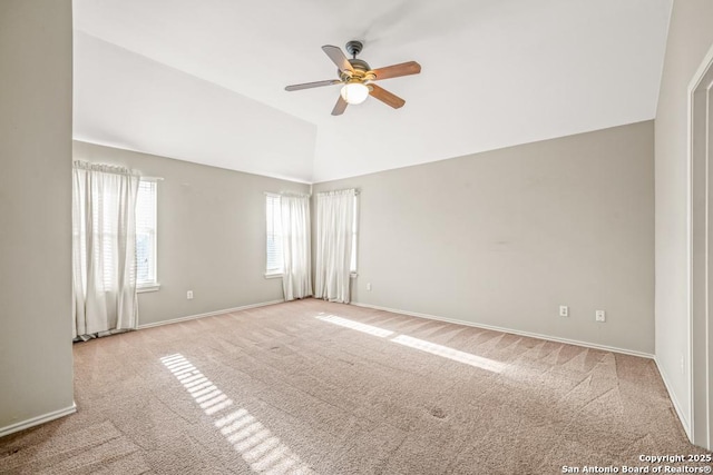 spare room featuring carpet floors, baseboards, vaulted ceiling, and a ceiling fan