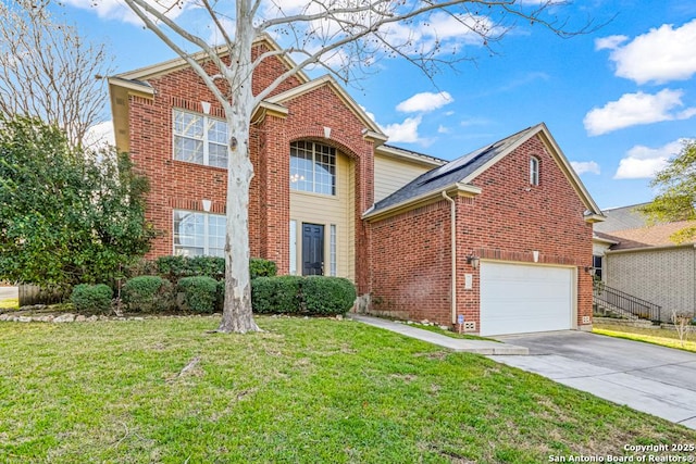 traditional-style home with brick siding, concrete driveway, an attached garage, roof mounted solar panels, and a front yard