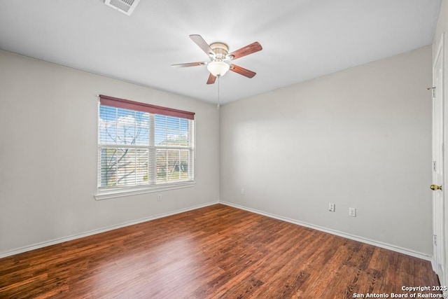 empty room with baseboards, visible vents, a ceiling fan, and wood finished floors