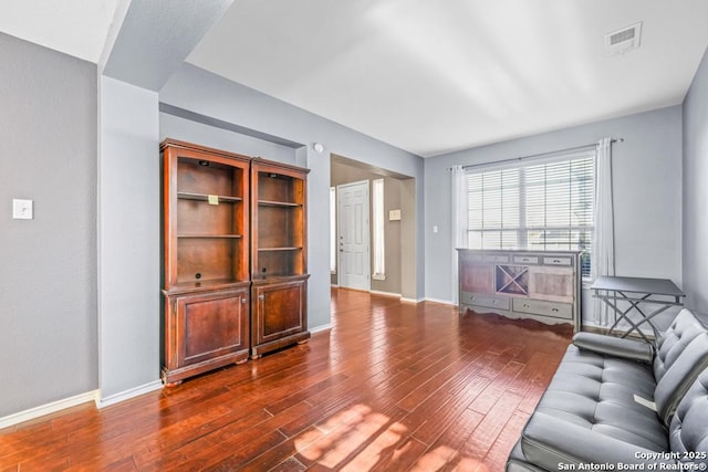 living area with baseboards, visible vents, and dark wood-style flooring