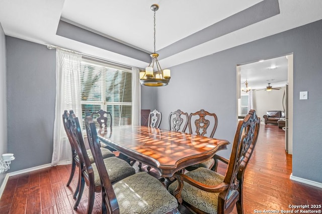 dining space featuring baseboards, a tray ceiling, and hardwood / wood-style floors