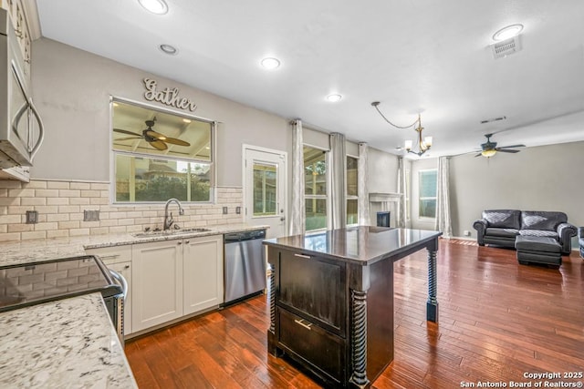 kitchen featuring appliances with stainless steel finishes, dark wood-style flooring, a sink, a fireplace, and backsplash