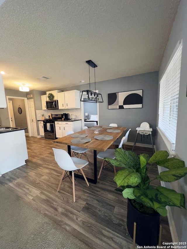 dining area featuring dark wood-type flooring and a textured ceiling