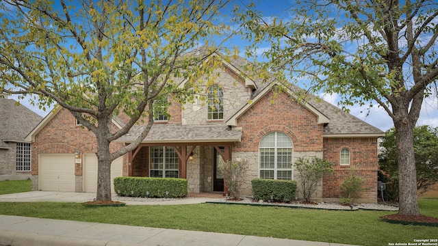 traditional-style house with a garage, stone siding, brick siding, and a front lawn