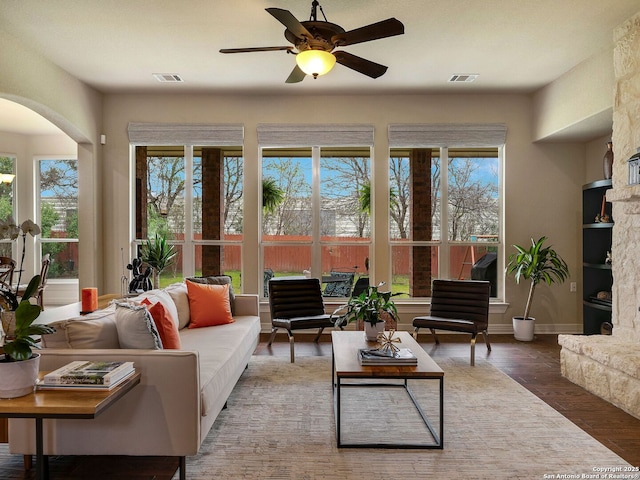 sunroom featuring a ceiling fan, arched walkways, and visible vents