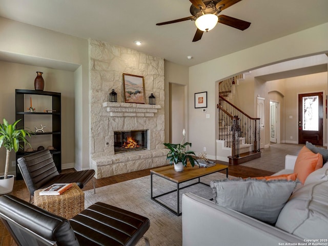 living room featuring a fireplace, stairway, baseboards, and wood finished floors