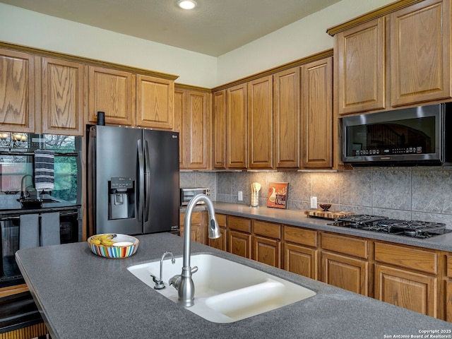 kitchen with tasteful backsplash, brown cabinetry, a sink, and black appliances