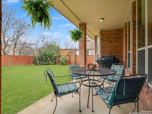 view of patio with outdoor dining area, a playground, grilling area, and a fenced backyard