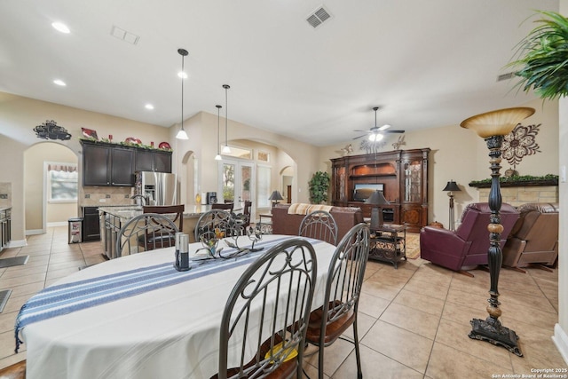 dining area featuring arched walkways, visible vents, ceiling fan, and light tile patterned flooring