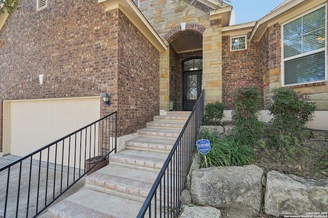 property entrance with stone siding, brick siding, and an attached garage