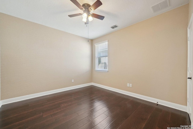 spare room featuring dark wood-type flooring, visible vents, and baseboards