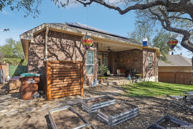 back of property featuring brick siding, a patio, roof mounted solar panels, ceiling fan, and fence