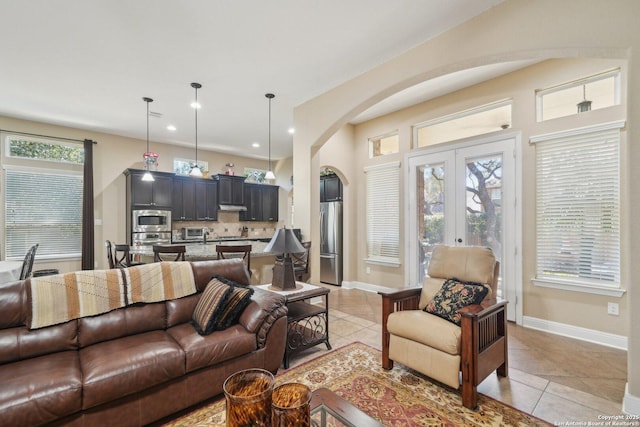 living room with arched walkways, light tile patterned flooring, and plenty of natural light